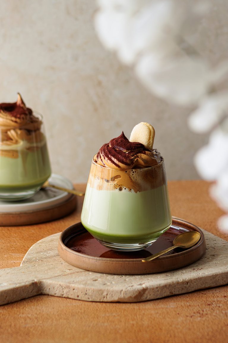 dalgona Kaffee, cremiger kaffee-mousse auf milch-matcha im glas. feiner Kakao ergänzt das edle Getränk – moderne, klare foodfotografie von natalia tag